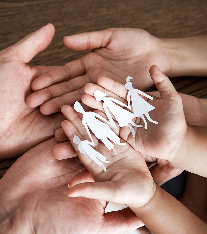 Hands holding paper cut-out of a family